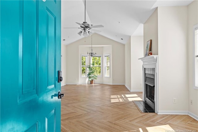 foyer entrance featuring ceiling fan, a tile fireplace, a chandelier, baseboards, and lofted ceiling
