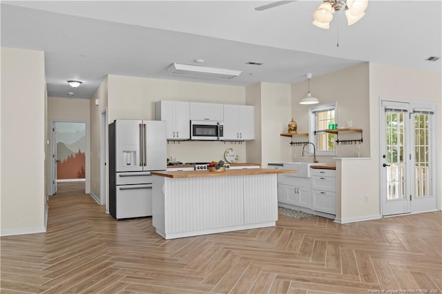 kitchen with white fridge with ice dispenser, butcher block countertops, white cabinetry, and baseboards