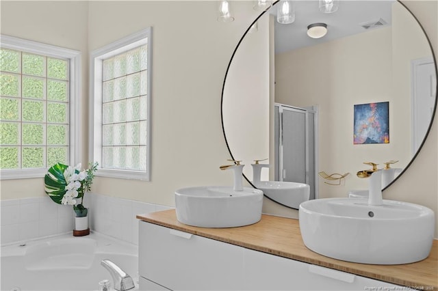 bathroom with a bath, a shower stall, and double vanity