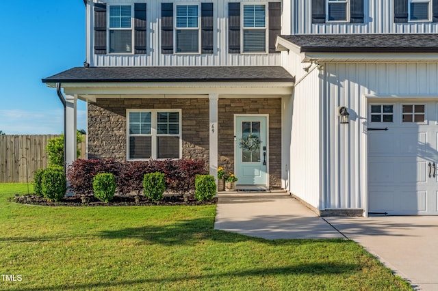 entrance to property with a porch, board and batten siding, driveway, and stone siding