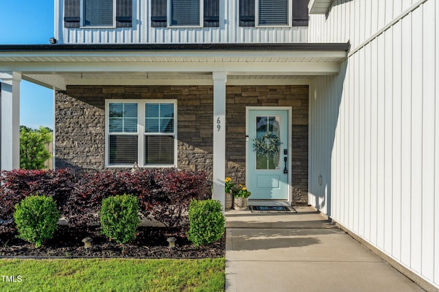property entrance featuring stone siding, covered porch, and board and batten siding