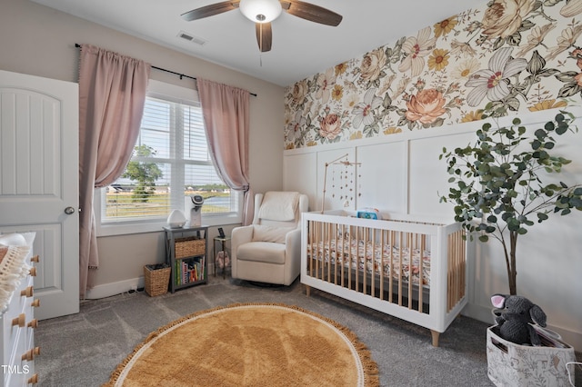 carpeted bedroom featuring wallpapered walls, a nursery area, and a ceiling fan