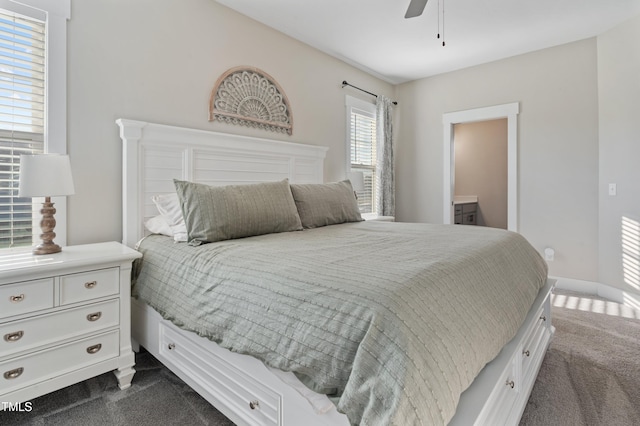 bedroom featuring dark colored carpet, ceiling fan, and ensuite bath