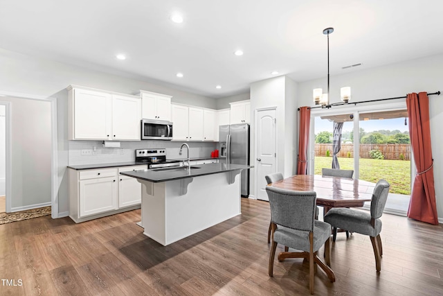 173 Longbow Dr, Middlesex, NC 27557 - kitchen featuring appliances with stainless steel finishes, dark countertops, a sink, white cabinetry, and a kitchen island with sink