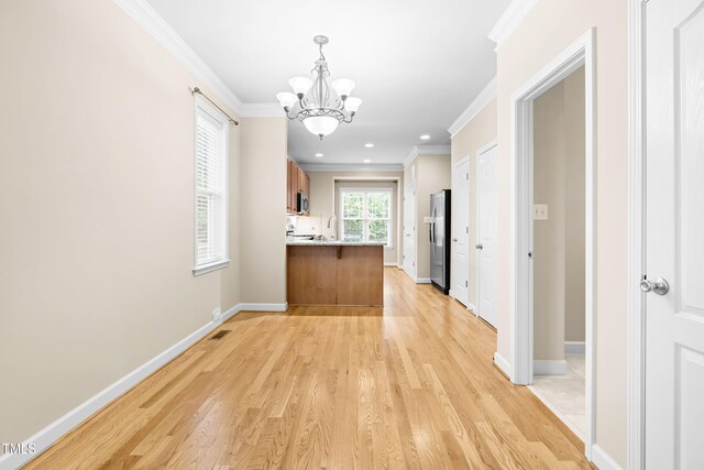 112 River Dell Townes Ave, Clayton, NC 27527 - kitchen with appliances with stainless steel finishes, a chandelier, crown molding, brown cabinets, and a peninsula