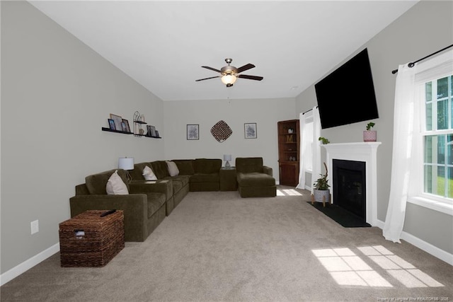 carpeted living area featuring ceiling fan, healthy amount of natural light, a fireplace with flush hearth, and baseboards