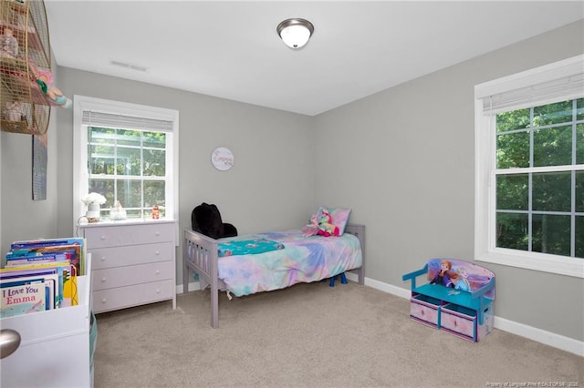 carpeted bedroom featuring multiple windows and baseboards