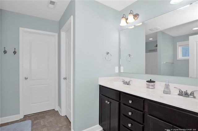 full bathroom featuring baseboards, stone finish flooring, and double vanity
