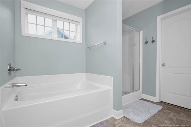 full bathroom featuring a stall shower, a bath, and baseboards