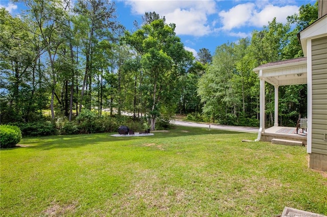 view of grassy yard featuring view of wooded area