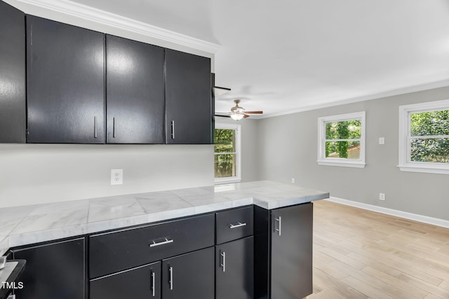 308 Lynn Rd, Durham, NC 27703 - kitchen with dark cabinetry, ceiling fan, a peninsula, baseboards, and light wood-style flooring