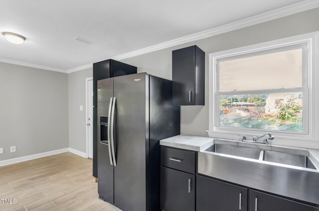 308 Lynn Rd, Durham, NC 27703 - kitchen with stainless steel refrigerator with ice dispenser, crown molding, dark cabinetry, baseboards, and light wood-type flooring