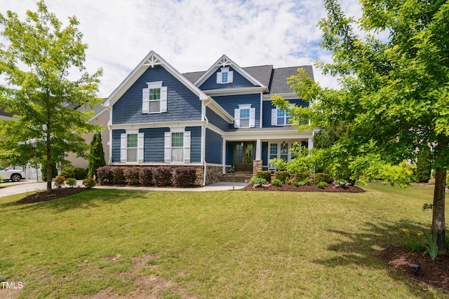 craftsman house with covered porch, a front lawn, and stone siding