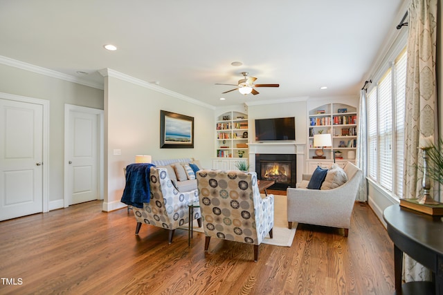 living area with a glass covered fireplace, wood finished floors, a ceiling fan, baseboards, and recessed lighting