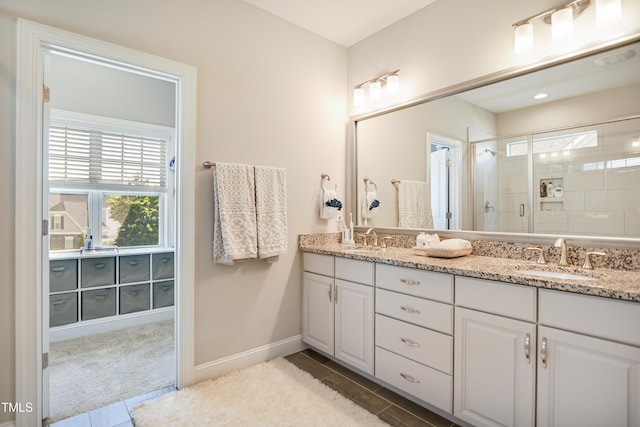 bathroom with plenty of natural light, a stall shower, double vanity, and baseboards