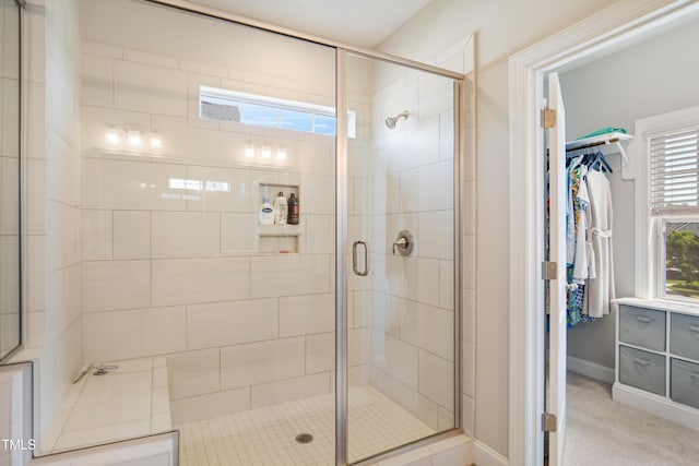 bathroom with a shower stall, baseboards, and a spacious closet