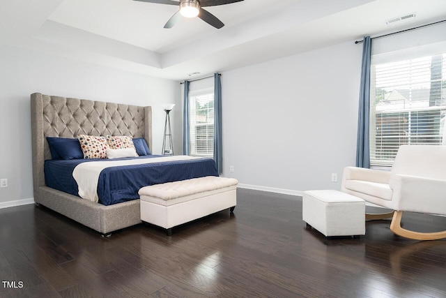 bedroom with dark wood finished floors, baseboards, a raised ceiling, and ceiling fan