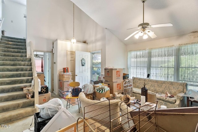 living area with stairway, a ceiling fan, and high vaulted ceiling