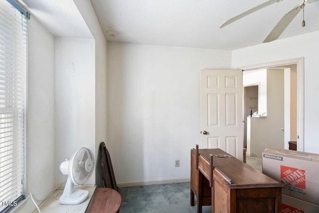 carpeted office space with ceiling fan and baseboards