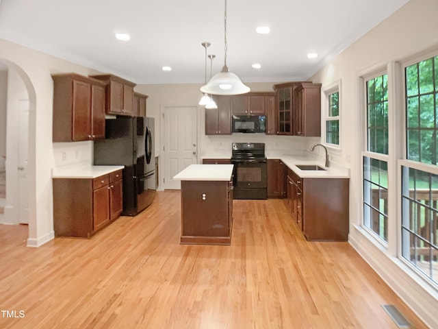 150 Remington Ct, Youngsville, NC 27596 - kitchen featuring black appliances, a sink, a center island, arched walkways, and light countertops