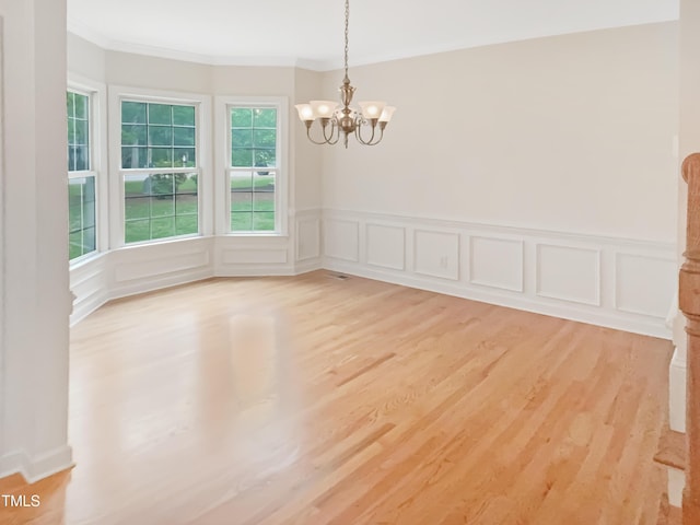150 Remington Ct, Youngsville, NC 27596 - unfurnished dining area featuring crown molding, a chandelier, light wood-type flooring, a wainscoted wall, and a decorative wall