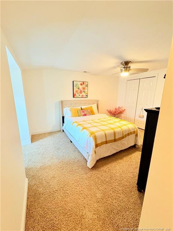 carpeted bedroom with a closet, ceiling fan, baseboards, and lofted ceiling