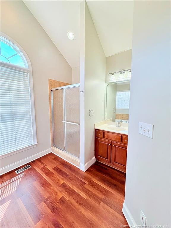 full bath with vaulted ceiling, a shower stall, wood finished floors, vanity, and baseboards