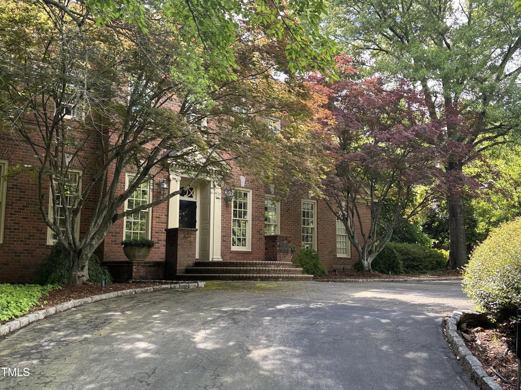 view of property hidden behind natural elements with brick siding
