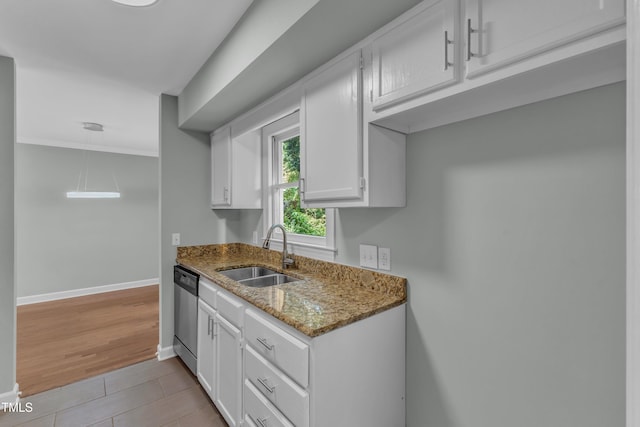 kitchen featuring a sink, dishwasher, light stone counters, baseboards, and white cabinets