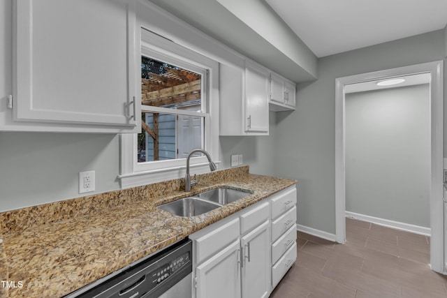 kitchen featuring a sink, white cabinetry, light stone counters, stainless steel dishwasher, and baseboards