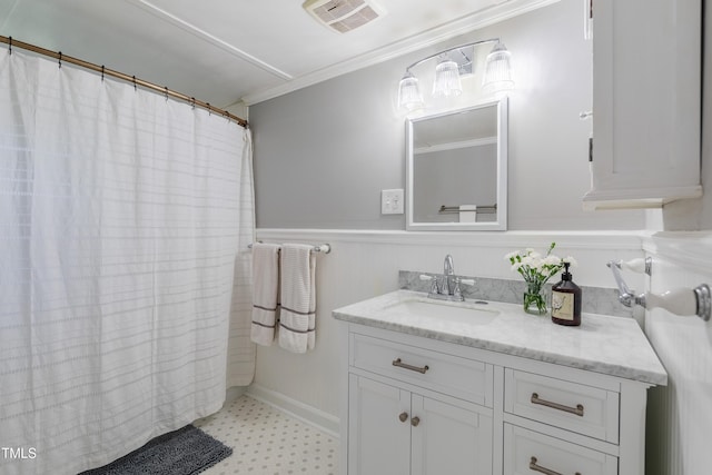full bathroom with crown molding, vanity, a wainscoted wall, and tile patterned floors