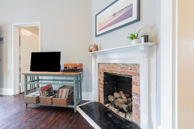 living area with a fireplace with raised hearth, wood finished floors, and baseboards