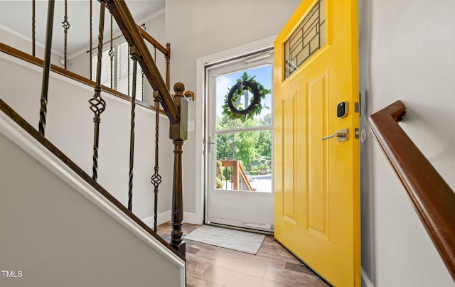 foyer entrance featuring stairs, wood finished floors, ornamental molding, and baseboards