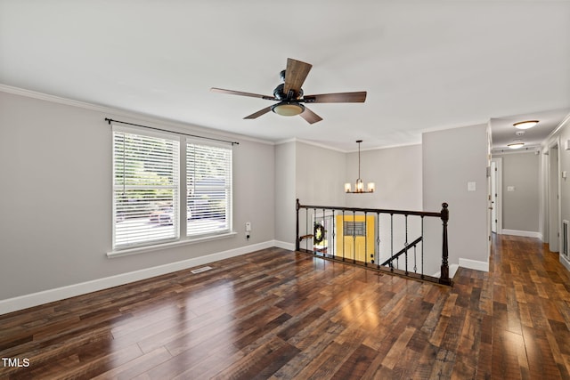 spare room featuring a chandelier, a ceiling fan, dark wood-style floors, baseboards, and ornamental molding