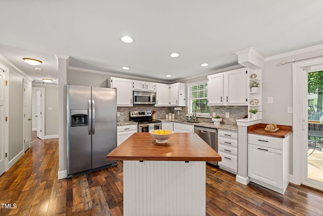 kitchen featuring appliances with stainless steel finishes, a sink, butcher block countertops, crown molding, and plenty of natural light