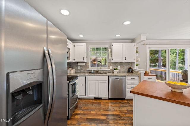 kitchen featuring stainless steel appliances, a sink, white cabinetry, dark wood finished floors, and tasteful backsplash