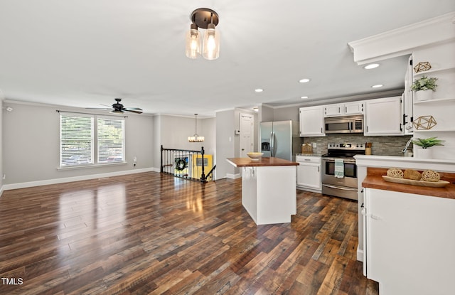 kitchen with appliances with stainless steel finishes, wooden counters, white cabinetry, ornamental molding, and decorative backsplash