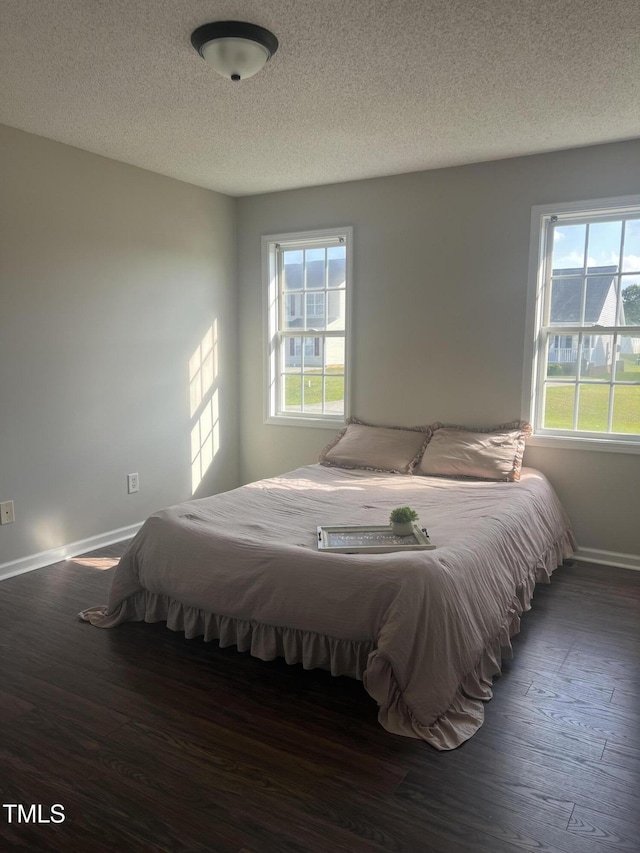 bedroom with baseboards, wood finished floors, and a textured ceiling