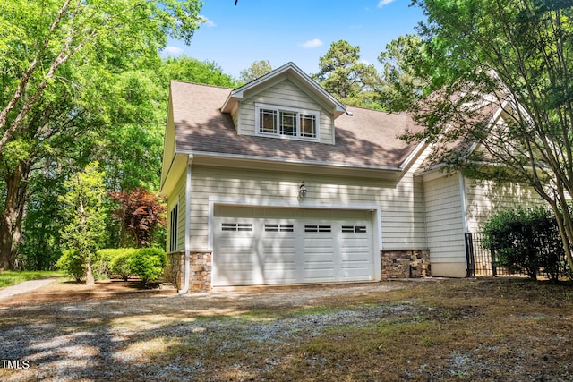 2819 Ellis Chapel Rd, Bahama, NC 27503 - view of front of property featuring dirt driveway, a garage, fence, stone siding, and roof with shingles