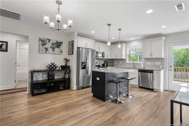 446 Placid Pond Dr, Broadway, NC 27505 - kitchen featuring stainless steel appliances, a sink, white cabinets, light wood-type flooring, and a center island