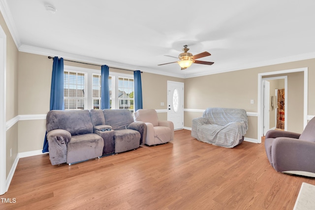 living area with crown molding, light wood-style floors, ceiling fan, and baseboards