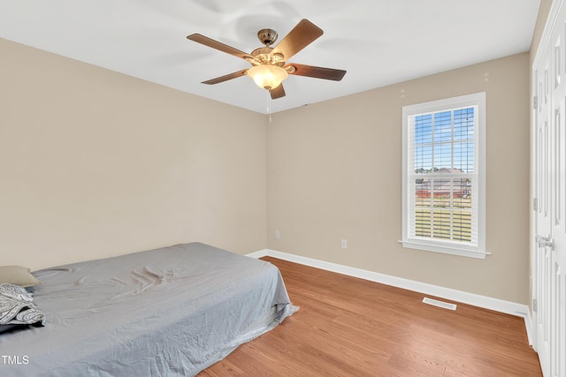 bedroom with baseboards, wood finished floors, and a ceiling fan