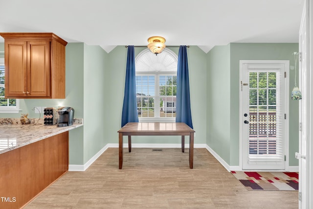dining area with light wood-type flooring, healthy amount of natural light, and baseboards