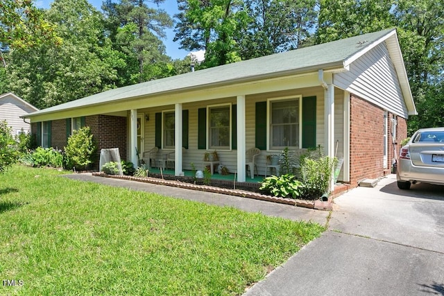 ranch-style house featuring covered porch, brick siding, a front yard, and concrete driveway