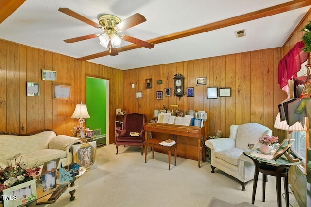 living area featuring carpet floors, a ceiling fan, and wood walls