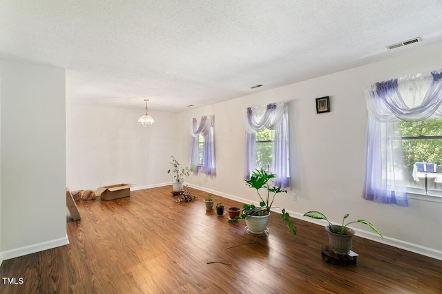 interior space with wood finished floors, a textured ceiling, baseboards, and a chandelier