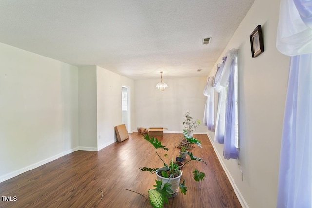 dining space featuring wood finished floors, a textured ceiling, a chandelier, and baseboards