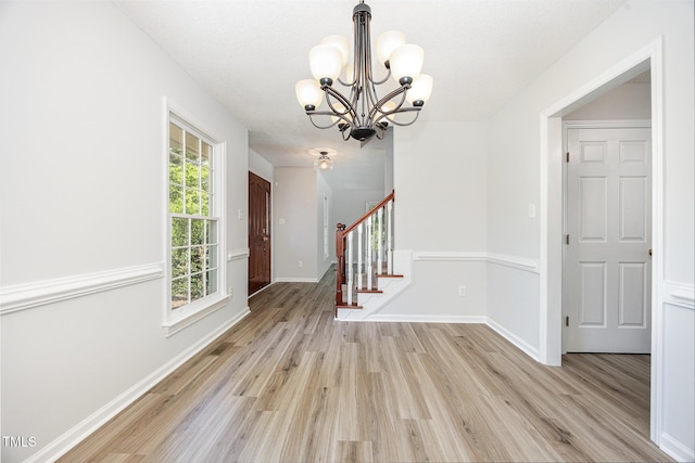 foyer entrance with a chandelier, light wood-style flooring, stairway, and baseboards