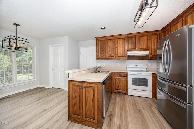 kitchen featuring stainless steel appliances, a sink, a chandelier, a peninsula, and under cabinet range hood