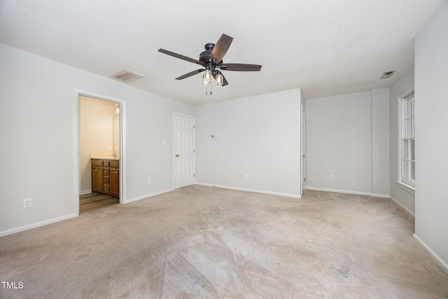 unfurnished bedroom featuring light carpet, baseboards, connected bathroom, and ceiling fan